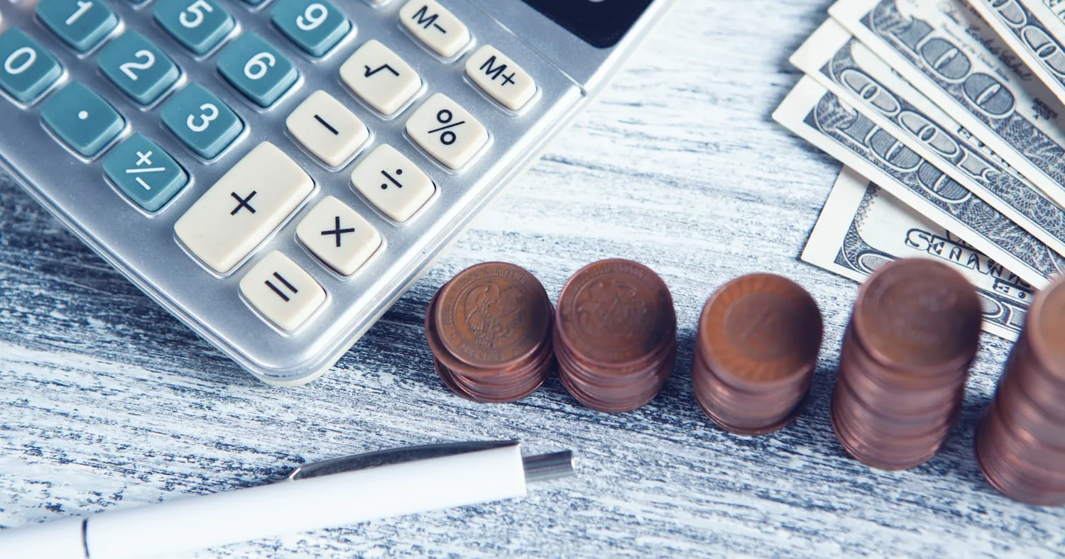 Calculatrice, stylo et billets posés sur une table