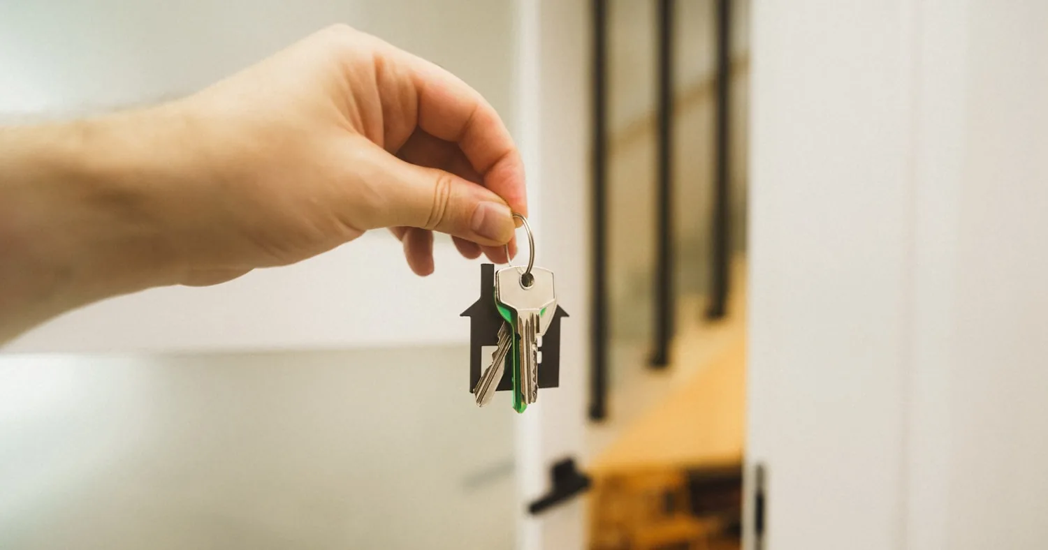 Main tenant une clé devant une porte